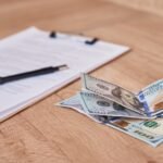 document pen and dollar bills on table close up RYP4FAF Hotel Paradise DLX